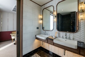 Bathroom features two sinks with separate mirrors, a herringbone-patterned tile design, and a geometric tile floor.