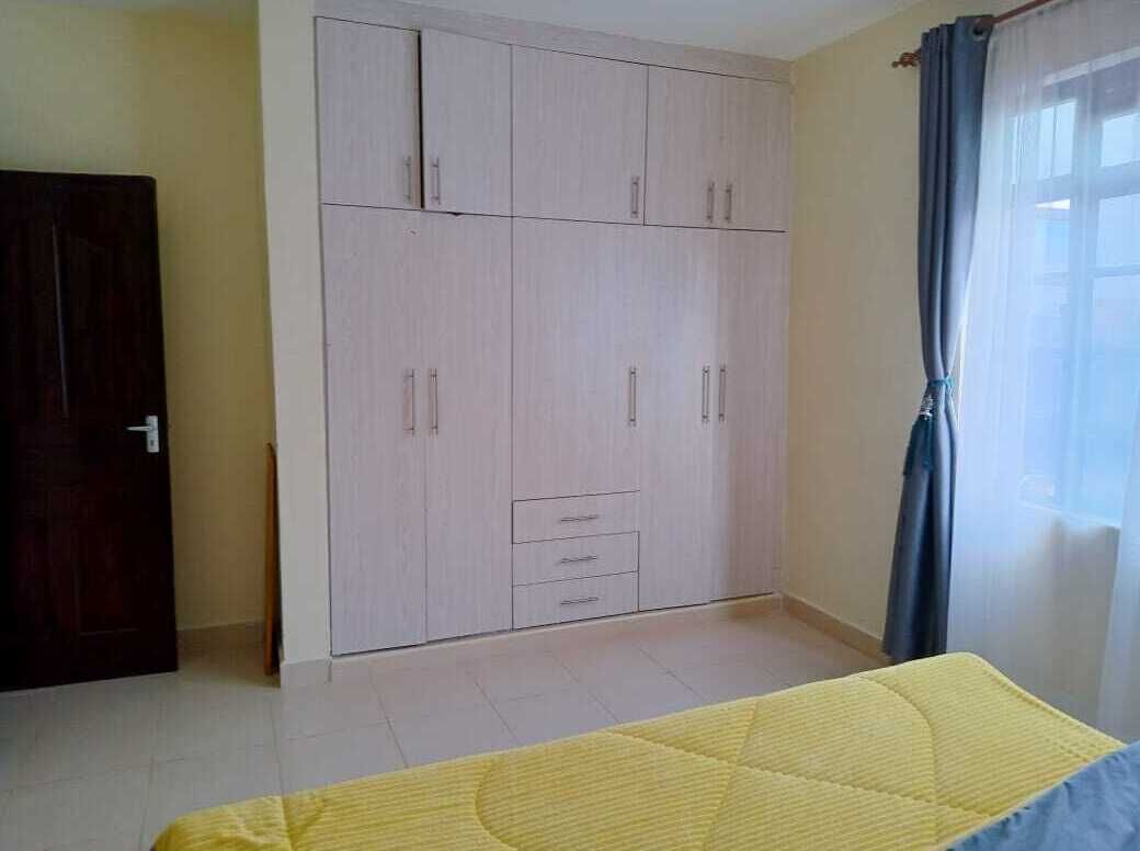 A bedroom with a bed, a wardrobe, and a window with curtains.