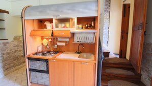 A compact kitchen with a gas stove, sink, and wooden cabinets.