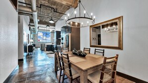 A spacious dining area with a wooden table and chairs, a large mirror on the wall, and exposed ductwork on the ceiling. - Crusader Bear Hut- Downtown Waco- Steps To The Silos (Waco)