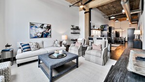 A modern living room with a sofa, armchairs, a coffee table, and a dining area in the background. - Crusader Bear Hut- Downtown Waco- Steps To The Silos (Waco)