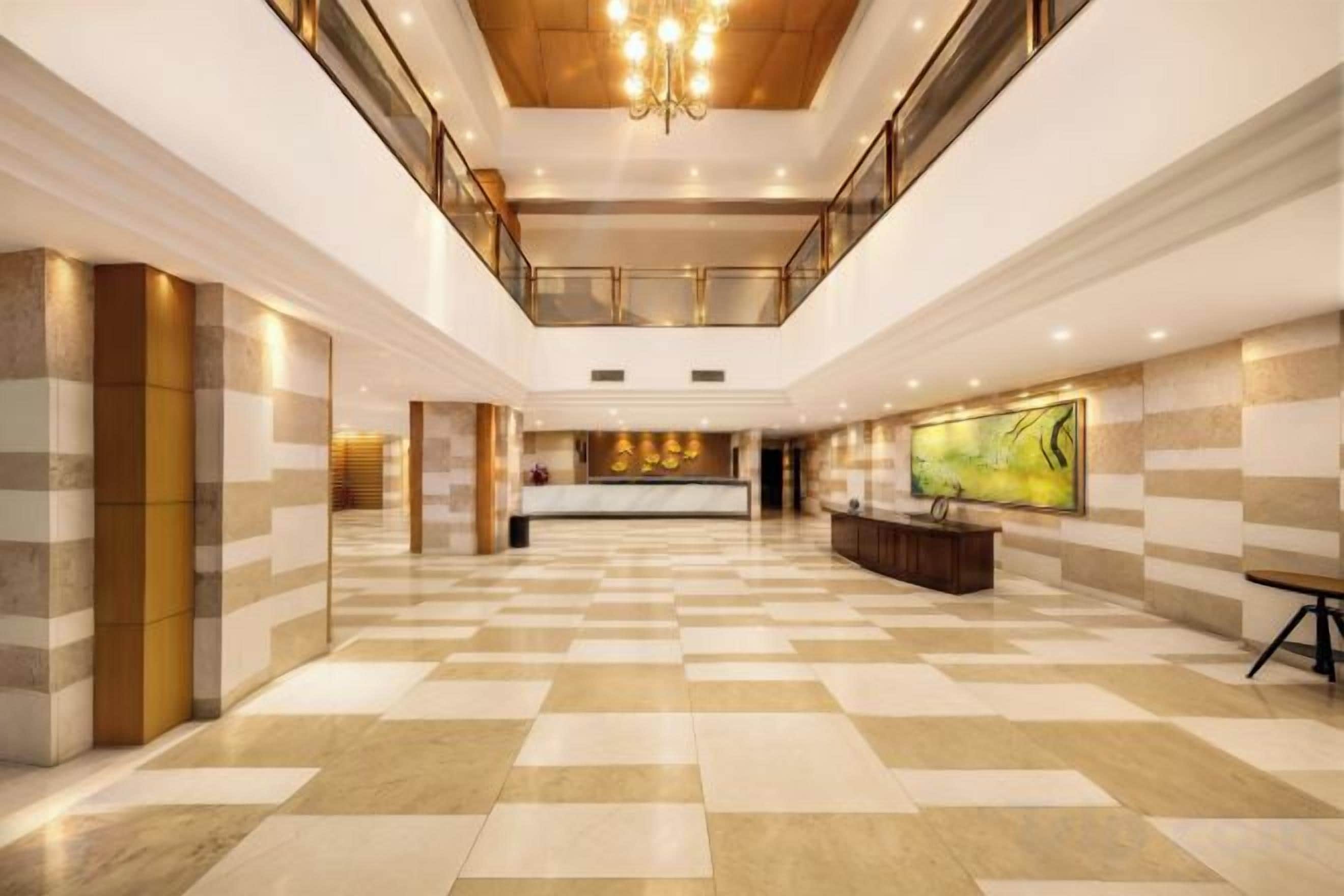 A spacious lobby with a checkered floor, a reception desk, and a large artwork on the wall.