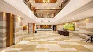 A spacious lobby with a checkered floor, a reception desk, and a large artwork on the wall.