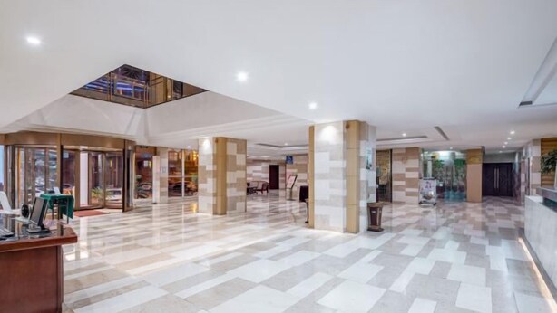 Eine geräumige Lobby mit hoher Decke, einem Glaselevator und einem Empfangstresen.