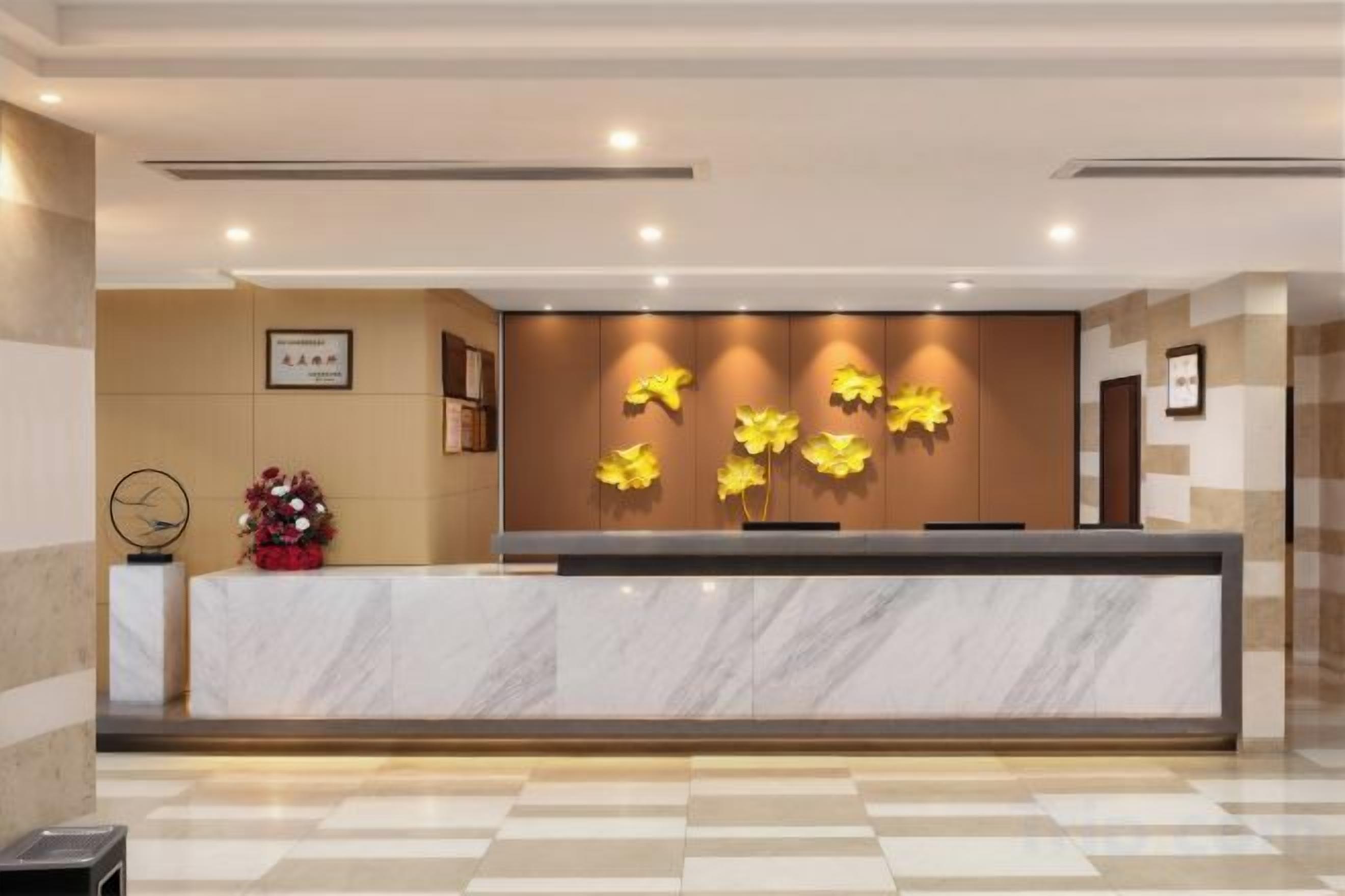 A reception desk with a marble top, a wall-mounted flower display, and a framed certificate on the wall.