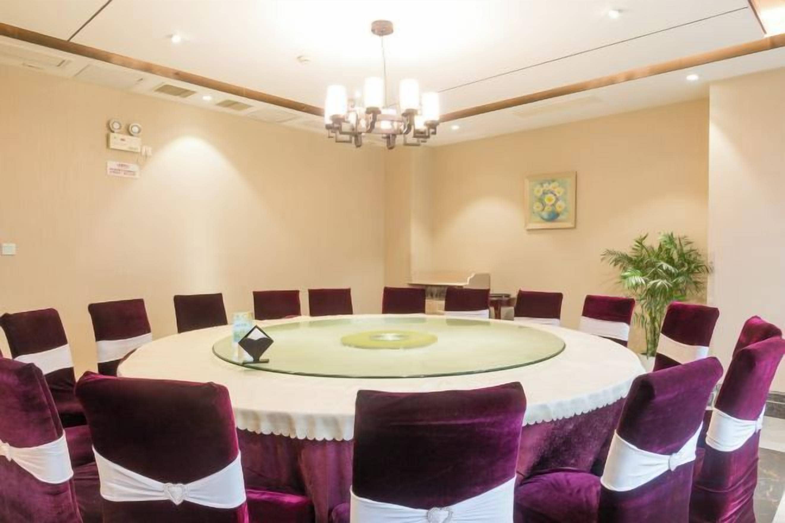 A conference room with a round table, chairs, and a chandelier.