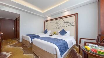 Habitación de hotel con dos camas, cabecera de madera con obra de arte, una mesita con fruta y una alfombra de cuero de vaca.