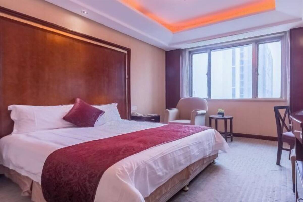 Una habitación de hotel con una cama grande, un escritorio, una silla, una mesita y una ventana.