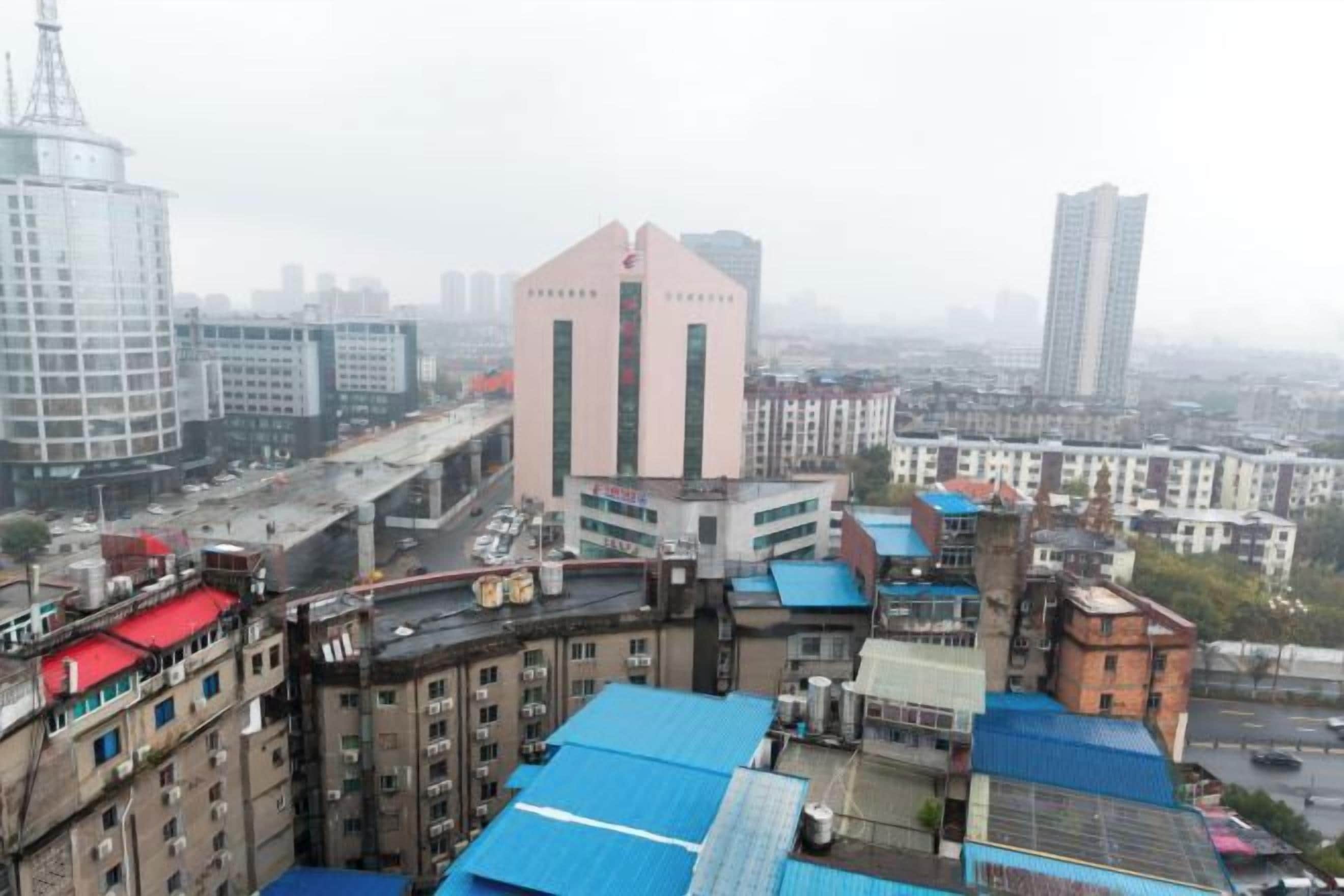 A cityscape with a prominent building with a pink facade and a blue-roofed structure in the foreground.