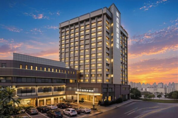 A multi-story hotel with a modern facade, a parking lot, and a clear sky. - Braim Seasons Hotel (Nanchang)