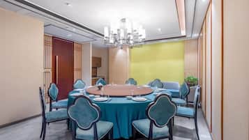 A conference room with a round table, teal chairs, and a chandelier.