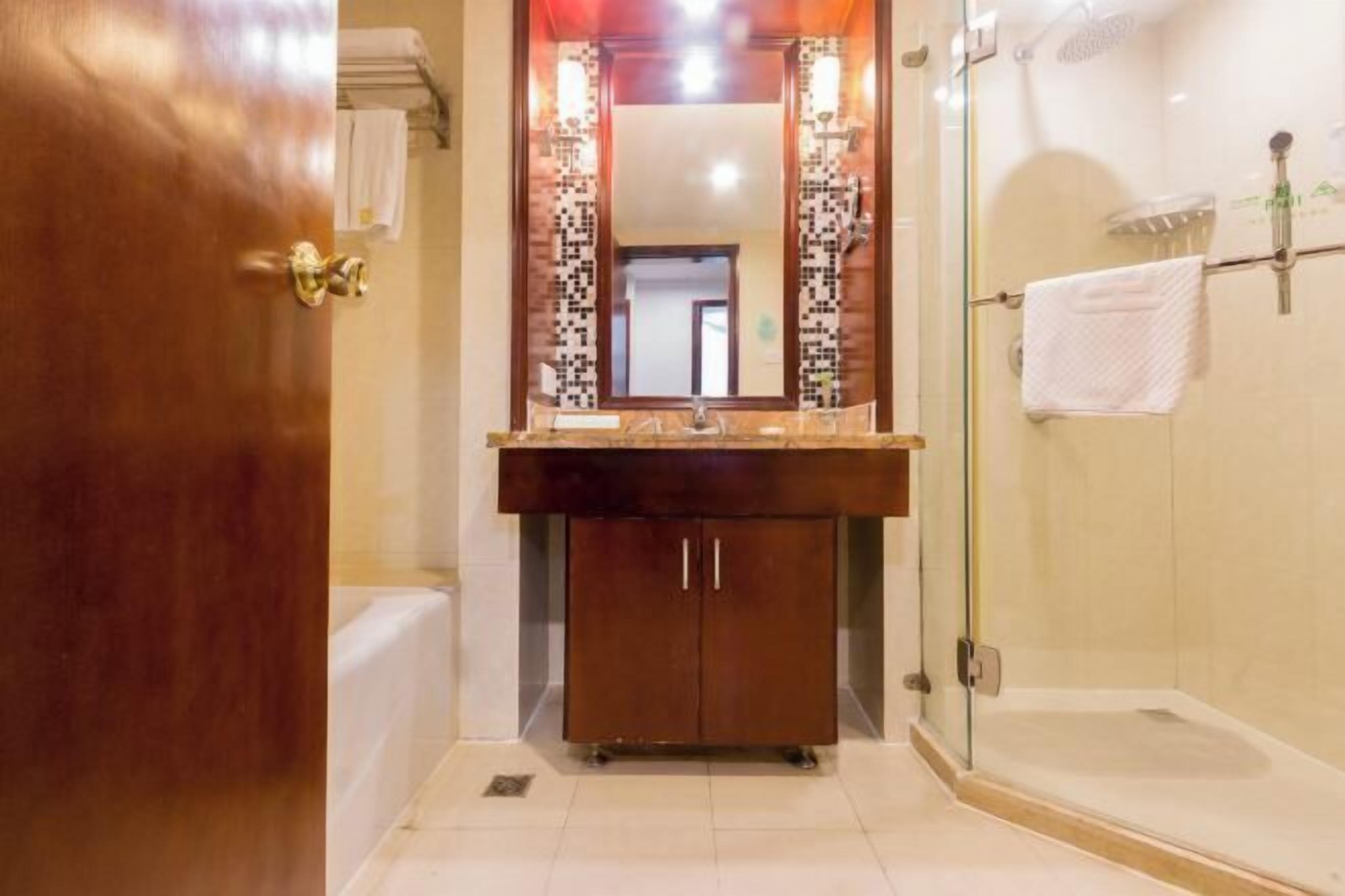 Un baño con puerta de madera, un lavabo con espejo y zona de ducha.
