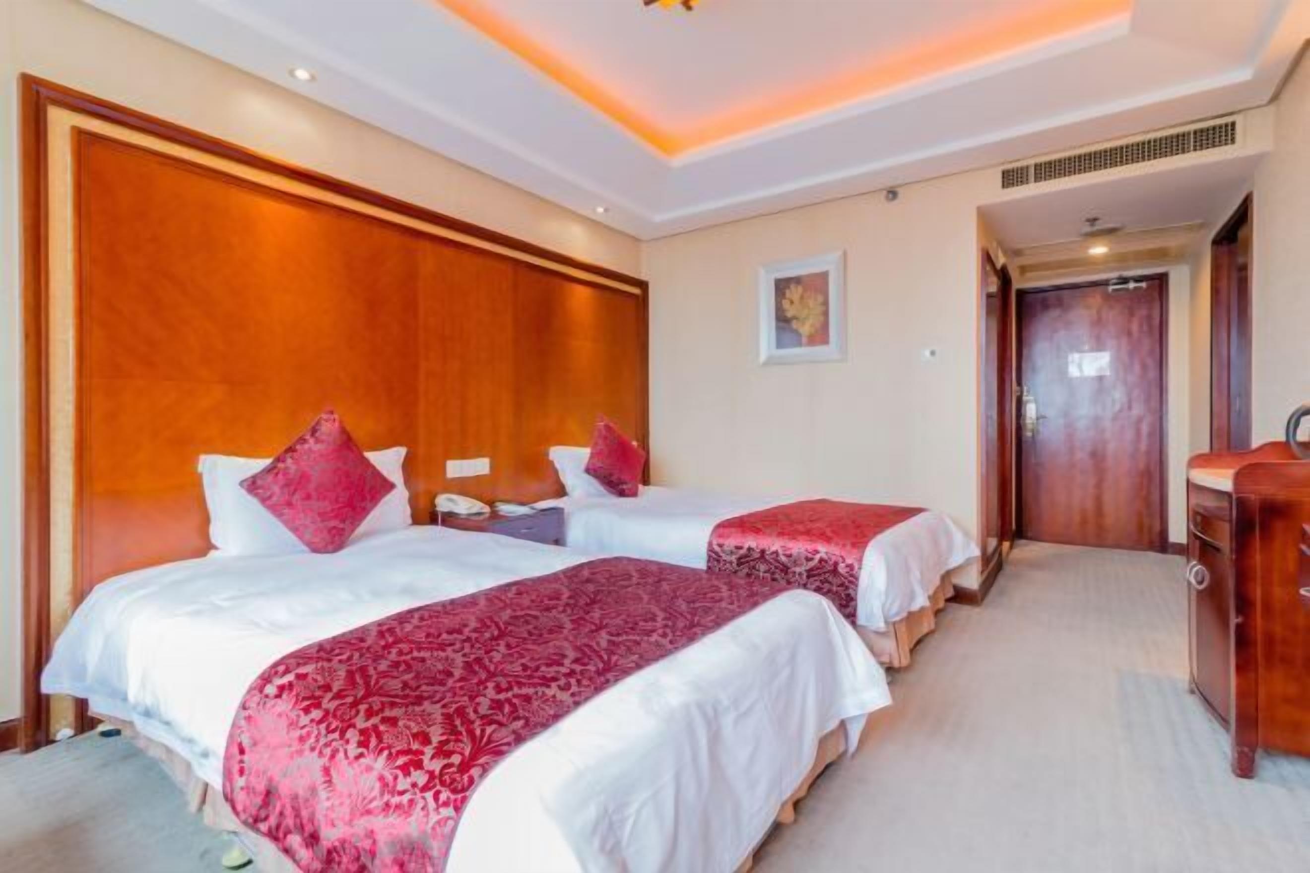 Een hotelkamer met twee bedden, een houten hoofdbord, een nachtkastje en een kledingkast.
