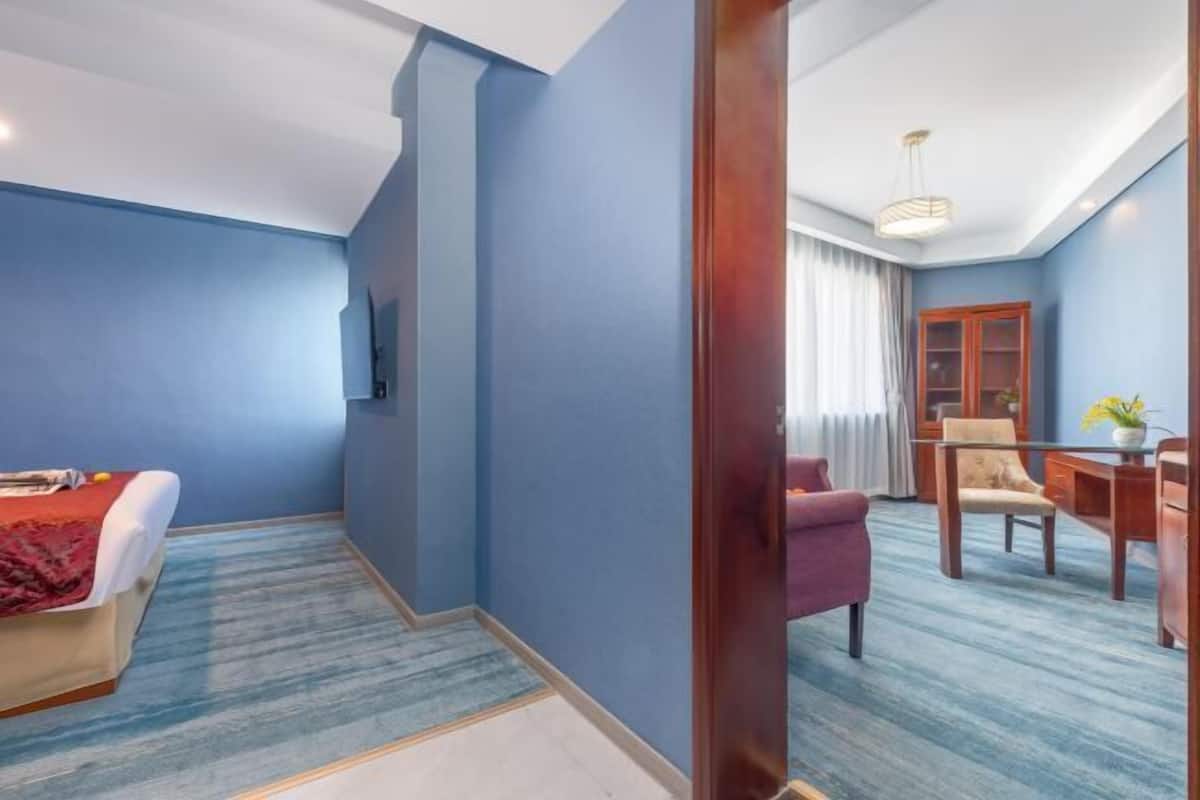 Una habitación de hotel con cama, escritorio, silla y zona de comedor.