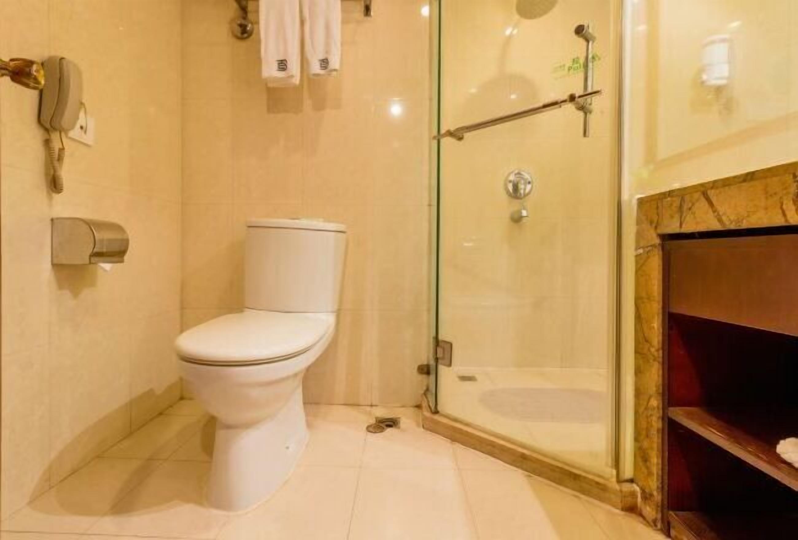 Ein Badezimmer mit Toilette, einer Duschkabine, einem Handtuchhalter und einem Telefon.