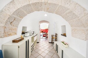 Un corridoio stretto con un arco in pietra che conduce a una zona cucina.