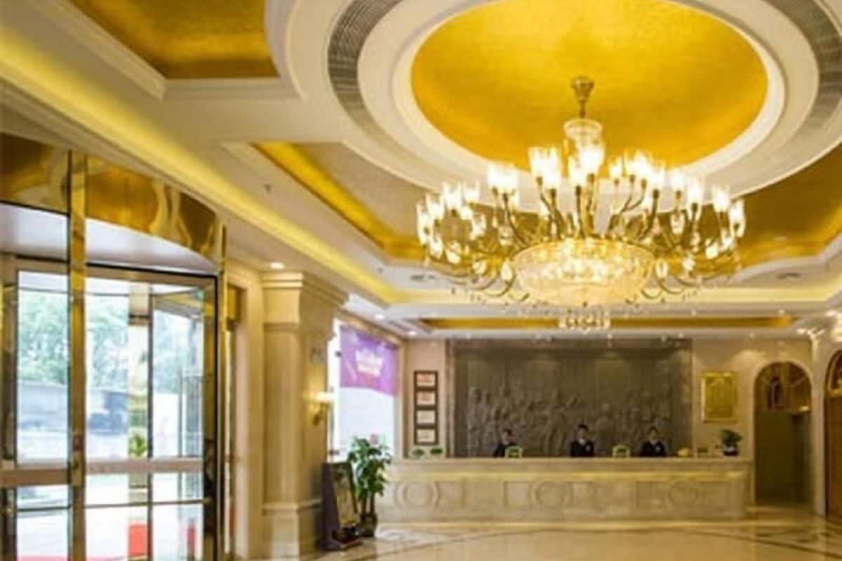 A lobby with a grand chandelier, a reception desk, and a polished floor.