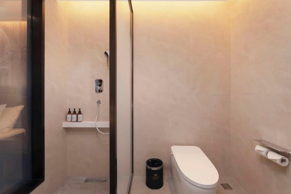 Un baño moderno con inodoro, ducha y un estante con artículos de aseo.