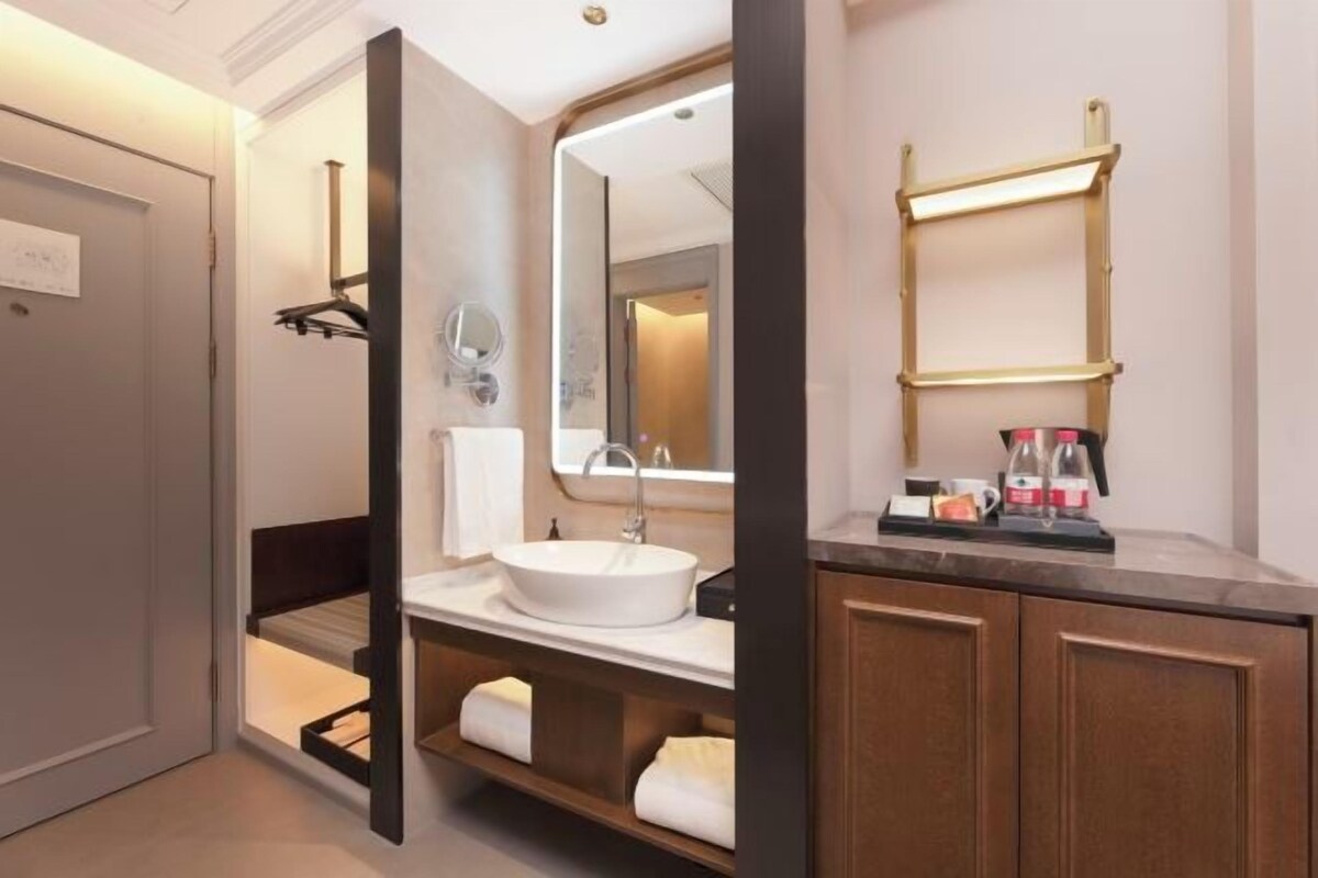 Un baño moderno con un espejo grande, un lavamanos redondo y un perchero para toallas.