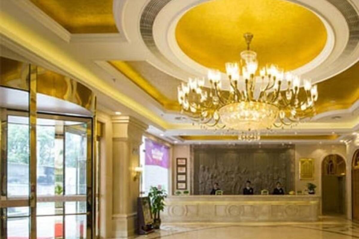 A lobby with a grand chandelier, a reception desk, and a polished floor.
