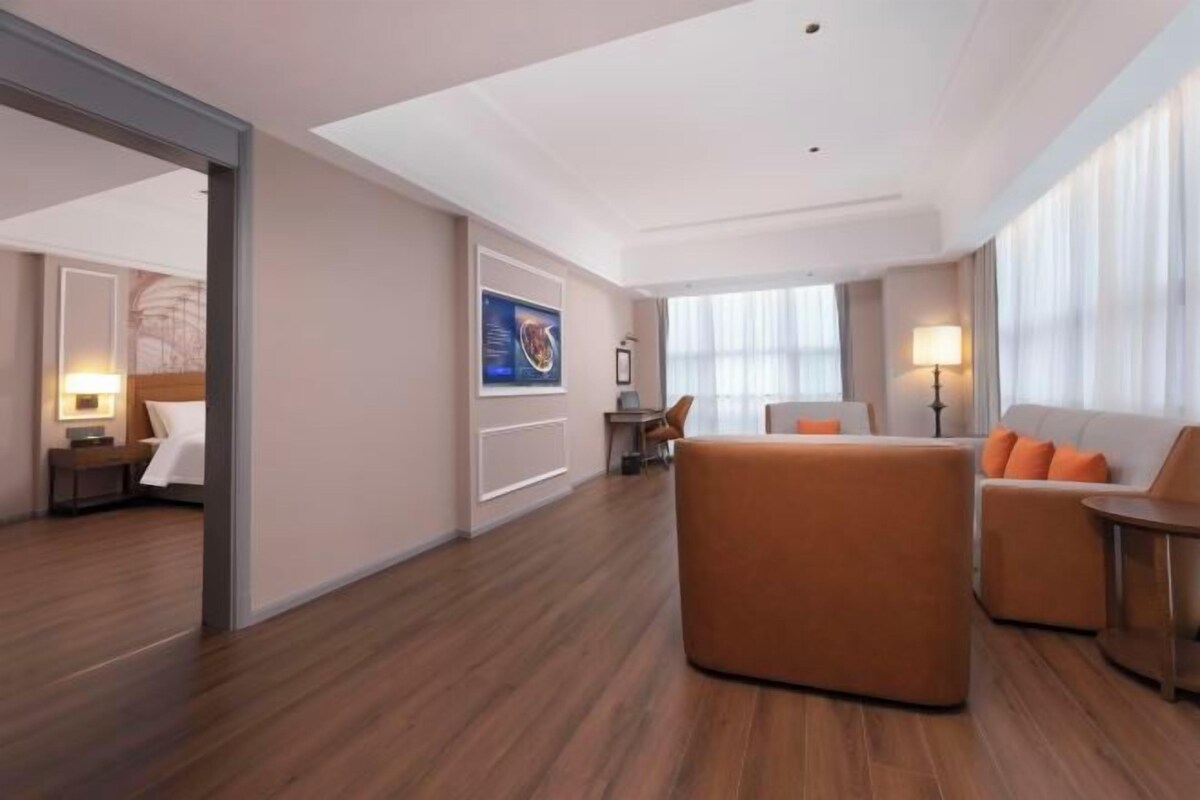 Une chambre d’hôtel avec un plancher en bois, un canapé, une chaise, un bureau et un lit.