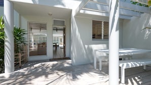 A modern outdoor seating area with a white table and bench, surrounded by white walls and columns. - Donovan's Reef | Port Douglas (Port Douglas)