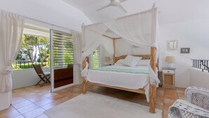 A bedroom with a four-poster bed, a balcony with a chair, and a ceiling fan. - Donovan's Reef | Port Douglas (Port Douglas)