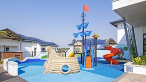 Un espace de jeux pour enfants avec un toboggan en forme de bateau et une structure d’escalade.