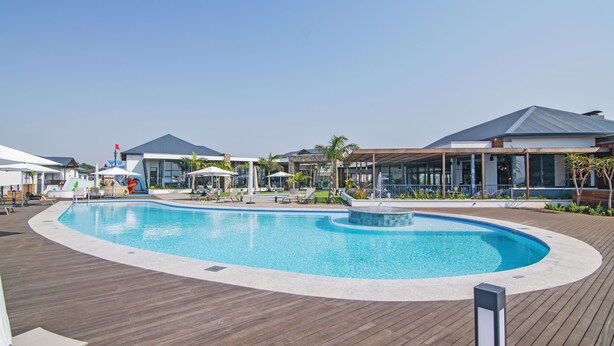 Une piscine avec une terrasse en bois, des chaises longues et des parasols.
