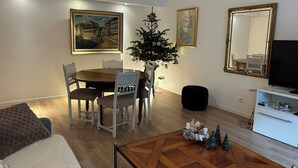 Un coin repas avec une table et des chaises en bois, un sapin de Noël et un tableau accroché au mur.