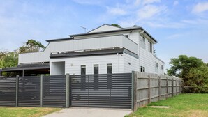 A modern two-story house with a flat roof, a covered porch, and a fenced backyard. - Sanctuary Lodge by Ready Set Stay (Cowes)