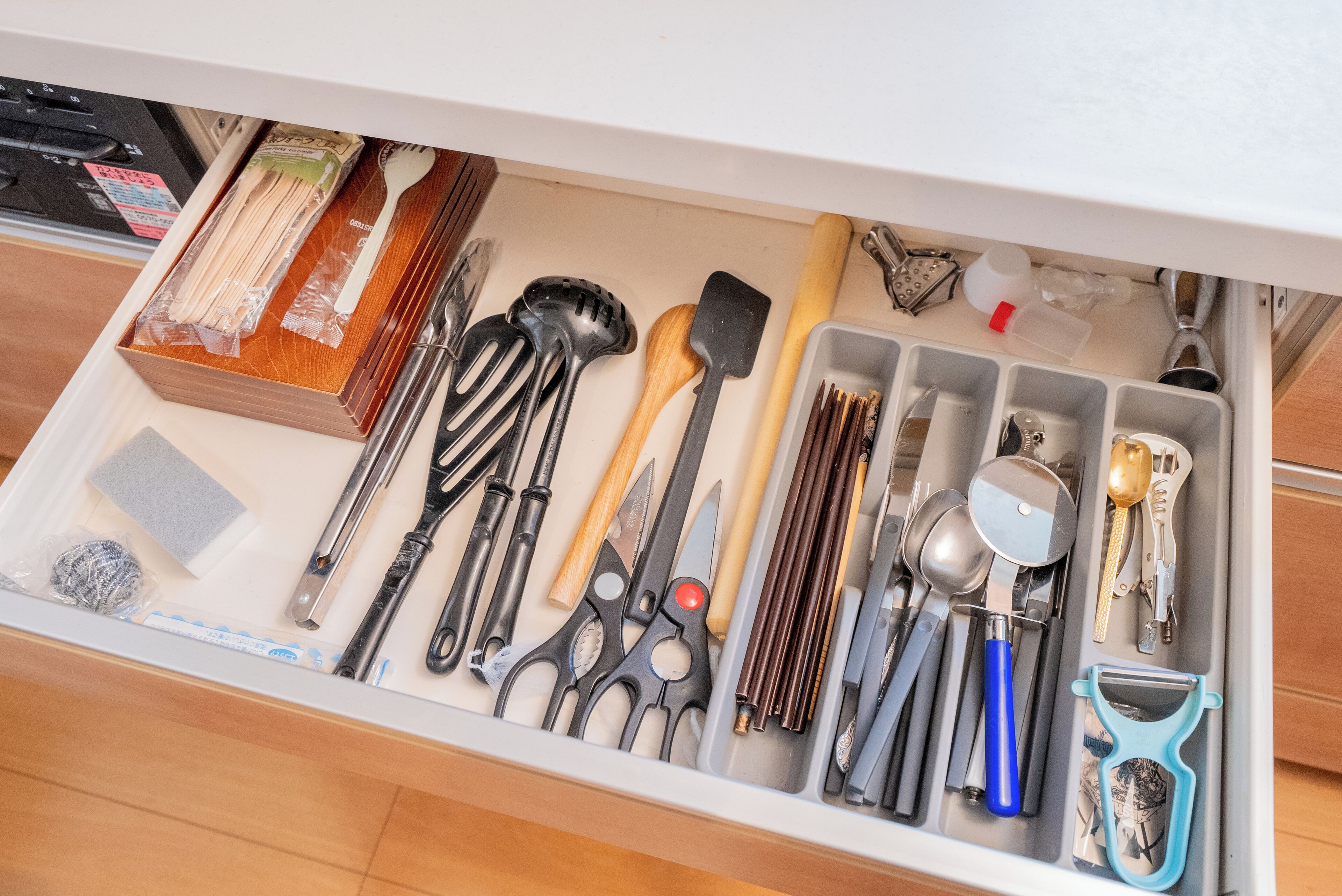 A drawer with various kitchen utensils and tools, including knives, spatulas, and a grater.