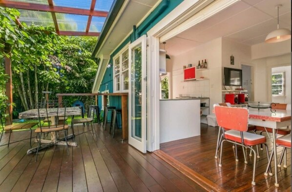 Enjoy the seamless indoor-outdoor connection in this open-plan living space with a kitchen, dining area, and outdoor deck.