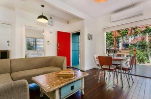 Relax in this inviting living area with a sofa, dining table, and balcony access to lush views.