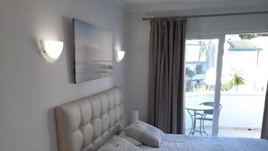 Une chambre avec un grand lit, une table de chevet, une lampe, une tête de lit, une fenêtre avec des rideaux et une vue sur l’extérieur.