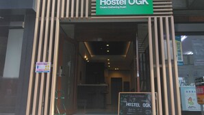 The exterior of Hostel OGK with a green signboard, wooden slats, and a welcoming entrance. - Hostel Ogk (Osaka)