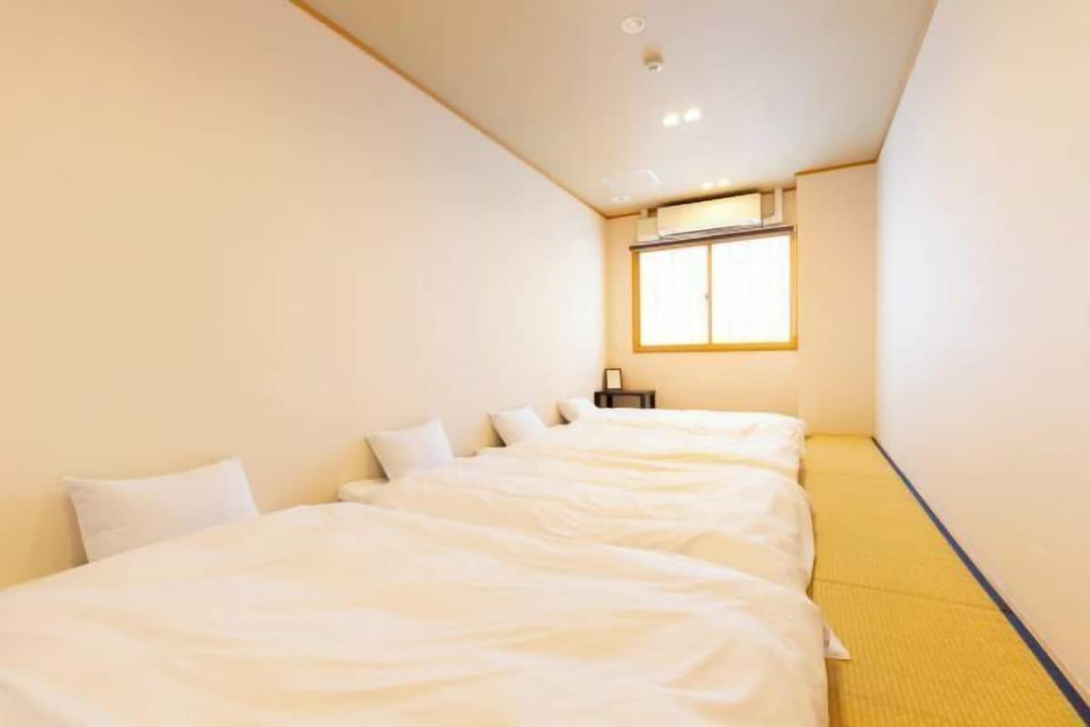 A hotel room with two beds, a window, and a bedside table.