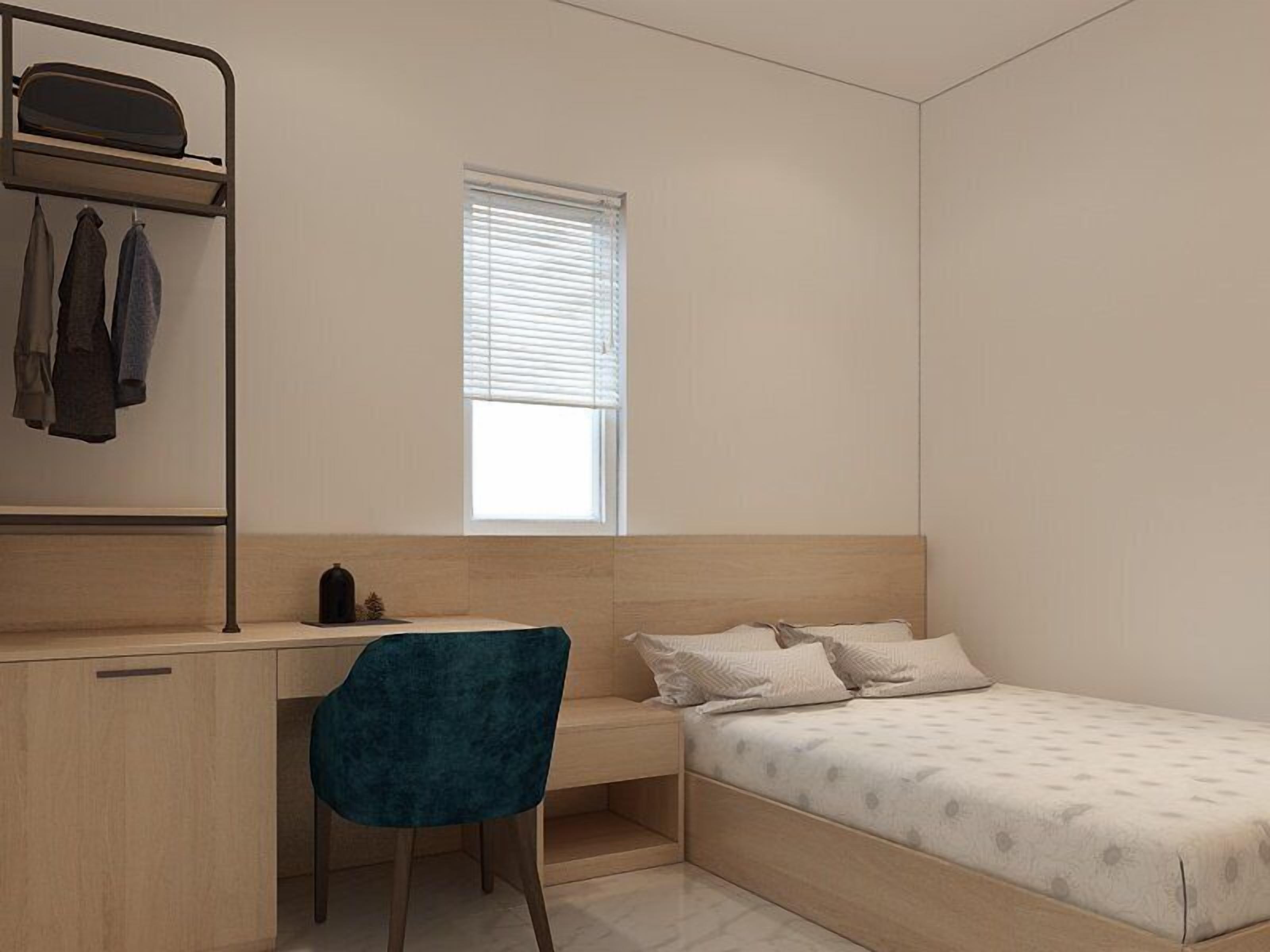 A compact bedroom with a single bed, a desk, and a chair.