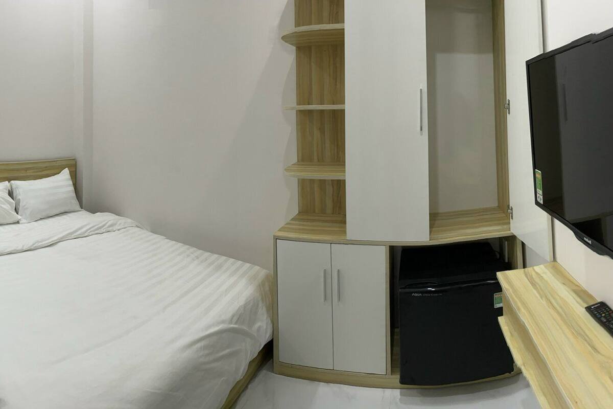 Une chambre à coucher avec un lit, une armoire, une télévision et un petit bureau.