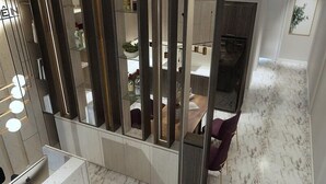 Un interior moderno con suelo de mármol, una zona de comedor con mesa y sillas, y una cocina con armarios y un refrigerador.