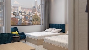 Una habitación de hotel moderna con dos camas, un sofá, una mesita pequeña y un ventanal con vistas a la ciudad.