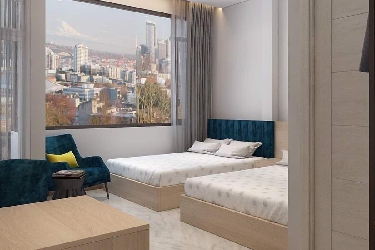 Une chambre d’hôtel moderne, équipée de deux lits, d’un canapé, d’une petite table et d’une grande fenêtre donnant sur le paysage urbain.