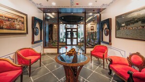 A room with a glass table, red upholstered chairs, and framed artwork on the walls. - The Chronicles by WSI - Near the Lake Pichola Udaipur (Udaipur)