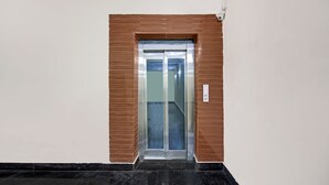 An elevator with a glass door, a control panel, and a security camera.