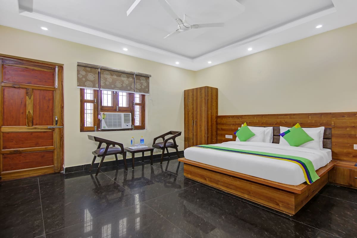 A hotel room with a bed, a desk, a wardrobe, and a ceiling fan.