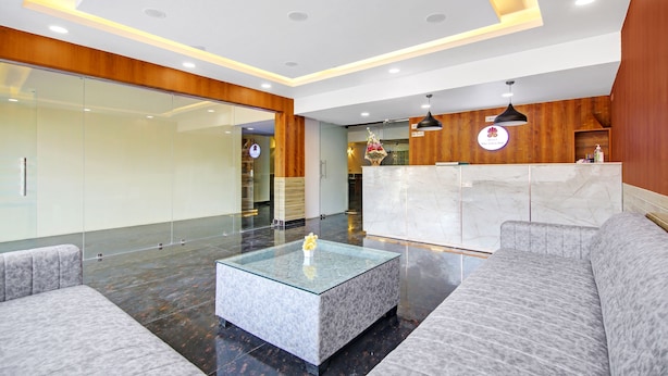 A modern hotel lobby with a reception desk, seating area, and a glass coffee table.