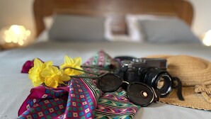 Una cama con una cámara, gafas y telas coloridas.