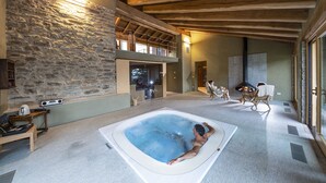 Un muro de piedra, un jacuzzi y un techo de madera.