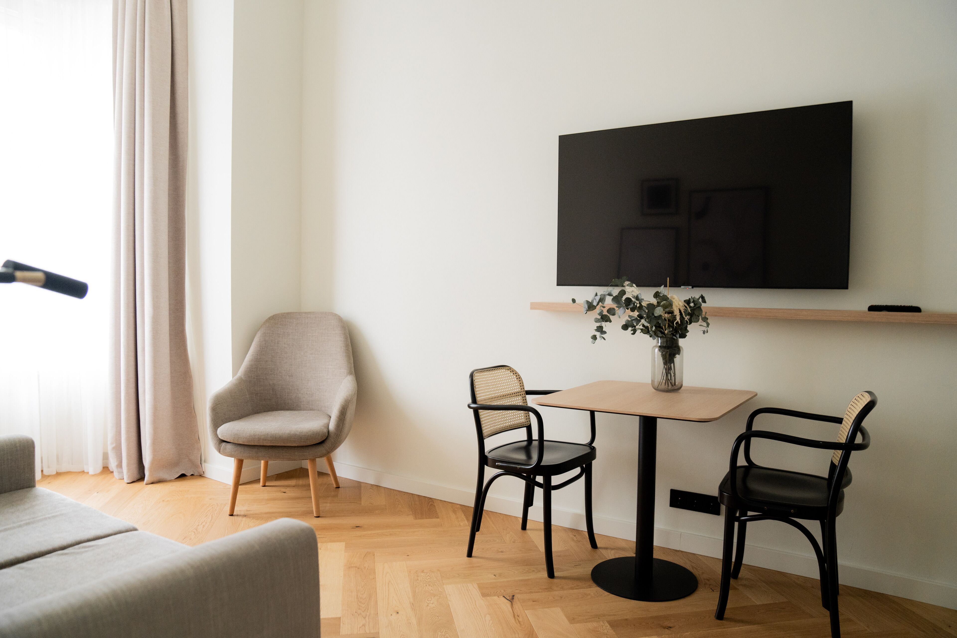 Una sala de estar moderna con un sofá, dos sillas, una mesa y un televisor de pantalla plana montado en la pared.