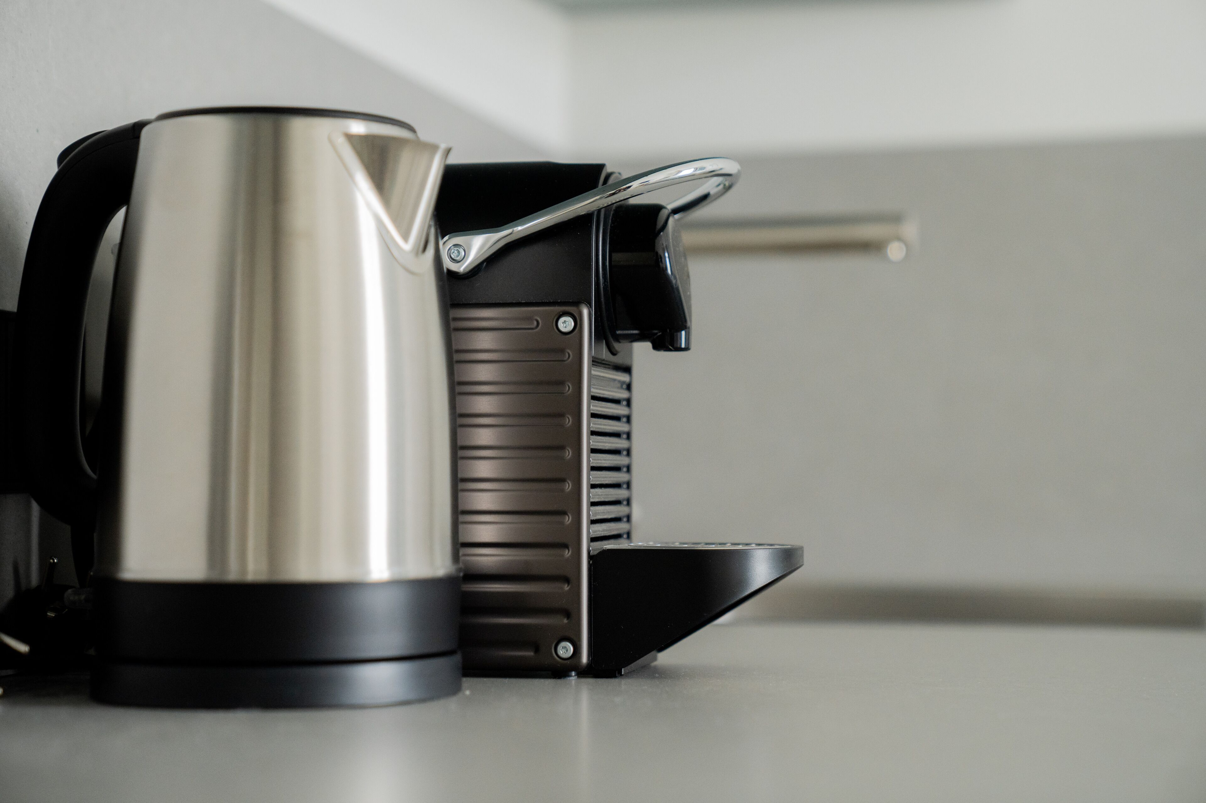 A stainless steel kettle and a black electric coffee maker on a countertop.